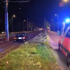 PKW steht auf Straßenbahngleisen bei Nacht neben einem Einsatzleitwagen mit eingeschaltetem Blaulicht.