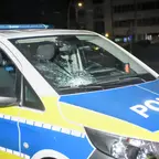 Polizeifahrzeug mit durch Steinwurf beschädigter Frontscheibe und sichtbarem Einschlagpunkt