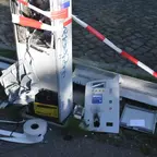Zerstörter Parkscheinautomat mit aufgerissener Front, verstreuten Teilen und Absperrband auf Kopfsteinpflaster.
