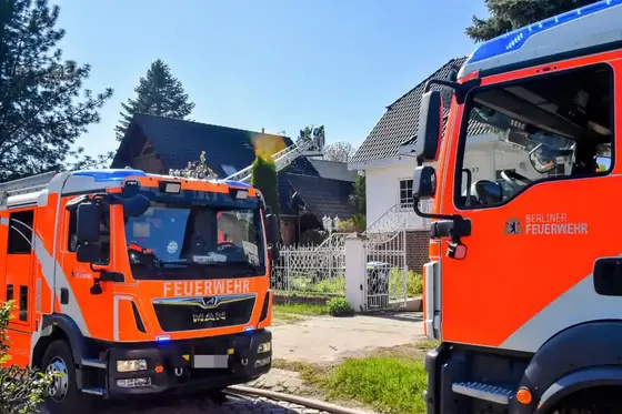 Zwei Feuerwehrfahrzeuge der Berliner Feuerwehr vor Wohnhäusern mit ausgefahrener Drehleiter