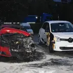 Zwei parkende Autos bei Nacht, eines vorne stark beschädigt und verbrannt, das andere mit Brandspuren an der Seite