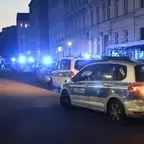 Mehrere Polizeiautos mit eingeschaltetem Blaulicht stehen in einer Straße vor mehrstöckigen Wohngebäuden in der Dämmerung.
