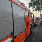 Rückansicht eines geparkten Feuerwehrfahrzeugs mit geschlossenen Rolltoren an einer Straße bei Dämmerung.