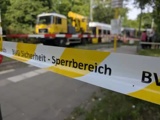 Flatterband mit der Aufschrift 'BVG Sicherheit - Sperrbereich' vor einer Baustelle mit gelbem Baugerät und Absperrung auf einem Gehweg
