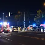 Nächtliche Straßenszene mit mehreren Einsatzfahrzeugen und Einsatzkräften an einer Kreuzung mit grünem Ampelsignal.