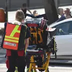 Rettungssanitäterin schiebt eine mit medizinischer Ausrüstung und Patient beladene Trage auf einer Straße