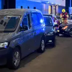 Nach einer Kollision zusammengeschobene Fahrzeuge am Straßenrand bei Nacht mit einem Feuerwehrmann in Schutzkleidung im Hintergrund.