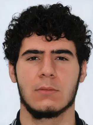 Porträt des Tatverdächtigen mit lockigem Haar, kurzem Bart und neutralem Gesichtsausdruck vor hellem Hintergrund.