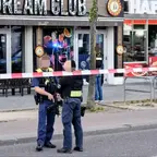 Zwei schwer bewaffnete Polizisten stehen hinter einer Absperrung vor dem Eingang eines Lokals mit der Aufschrift 'DREAM CLUB' und 'HAPPY'.