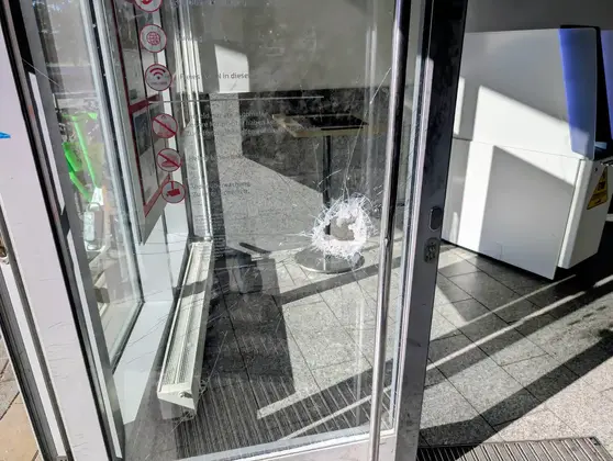 Glas-Eingangstür einer Sparkasse mit einem deutlichen Einbruchspuren in der Scheibe.