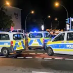 Zahlreiche Polizeifahrzeuge mit Blaulicht stehen nachts auf einer Straße.