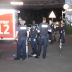 Mehrere Polizisten stehen nachts vor einem Einsatzfahrzeug mit der Aufschrift 'NOTRUF 112'