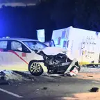Unfallstelle bei Nacht mit umgekipptem Wohnmobil und stark beschädigtem Auto auf der Straße, Einsatzkräfte in Warnkleidung vor Ort.