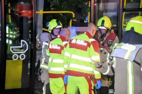 Mehrere Feuerwehrleute in Schutzkleidung und Helmen stehen vor einem Bus und führen eine Rettungsaktion durch.