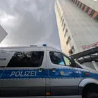 Polizeiwagen der Kriminaltechnik vor einem hohen Gebäude.