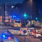 Morgendliche Straßenkreuzung mit mehreren Fahrzeugen, darunter Bus, Lkw und Pkw, einige mit eingeschalteten Blaulichtern.