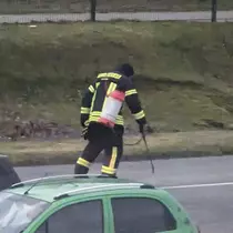 Feuerwehrmann in Schutzkleidung mit Sprühgerät geht auf einer Parkplatz und stumpft die Betriebsmittel ab.