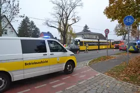 Weißer Transporter mit gelbem Streifen und Aufschrift 'Betriebsaufsicht' steht auf einem Radweg neben einer Straße mit mehreren Fahrzeugen, darunter eine gelbe Straßenbahn und ein Einsatzfahrzeug mit Blaulicht.