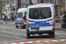 Rückansicht zweie Polizeivans mit blauer Beschriftung 'POLIZEI' auf einer Straße in einer Stadt.