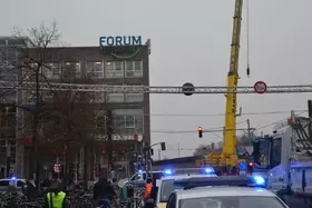Straßenszene mit mehreren Einsatzfahrzeugen mit Blaulicht, einem gelben Kran und einem Gebäude mit dem Schriftzug 'FORUM Köpenick'.