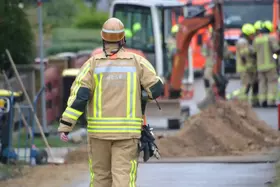 Mitarbeiter der Netzgesellschaft Berlin-Brandenburg, in gelber Schutzkleidung und Helm geht auf eine Baustelle mit Bagger und mehreren Einsatzkräften zu.