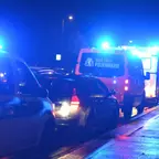 Mehrere Einsatzfahrzeuge der Polizei und Berliner Feuerwehr mit eingeschalteten Blaulichtern stehen nachts auf einer nassen Straße.