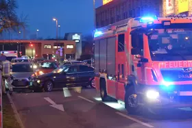 Feuerwehrauto mit Blaulicht auf der Straße, dahinter schwarzer BMW und silberner Hyundai in einem Unfall verwickelt.