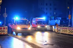 Zwei Einsatzfahrzeuge mit eingeschaltetem Blaulicht stehen nachts auf einer gesperrten Straße mit Absperrungen und Verkehrszeichen.