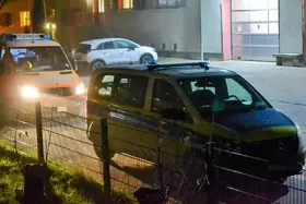 Polizeifahrzeug vor Feuerwehrfahrzeug mit eingeschaltetem Scheinwerfer vor einer Feuerwache.