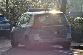 Polizeifahrzeug steht auf einer Straße, im Hintergrund Bäume und ein weiteres Fahrzeug.