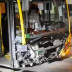 Vorderer Bereich eines gelben Busses mit fehlender Frontverkleidung, sichtbar sind technische Bauteile und offene Tür des Busses.