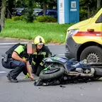 Die Polizei untersucht zusammen mit der Feuerwehr ein auf der Seite liegendes Motorrad auf der Straße, daneben steht ein gelbes Rettungsfahrzeug des Arbeiter-Samariter-Bund.