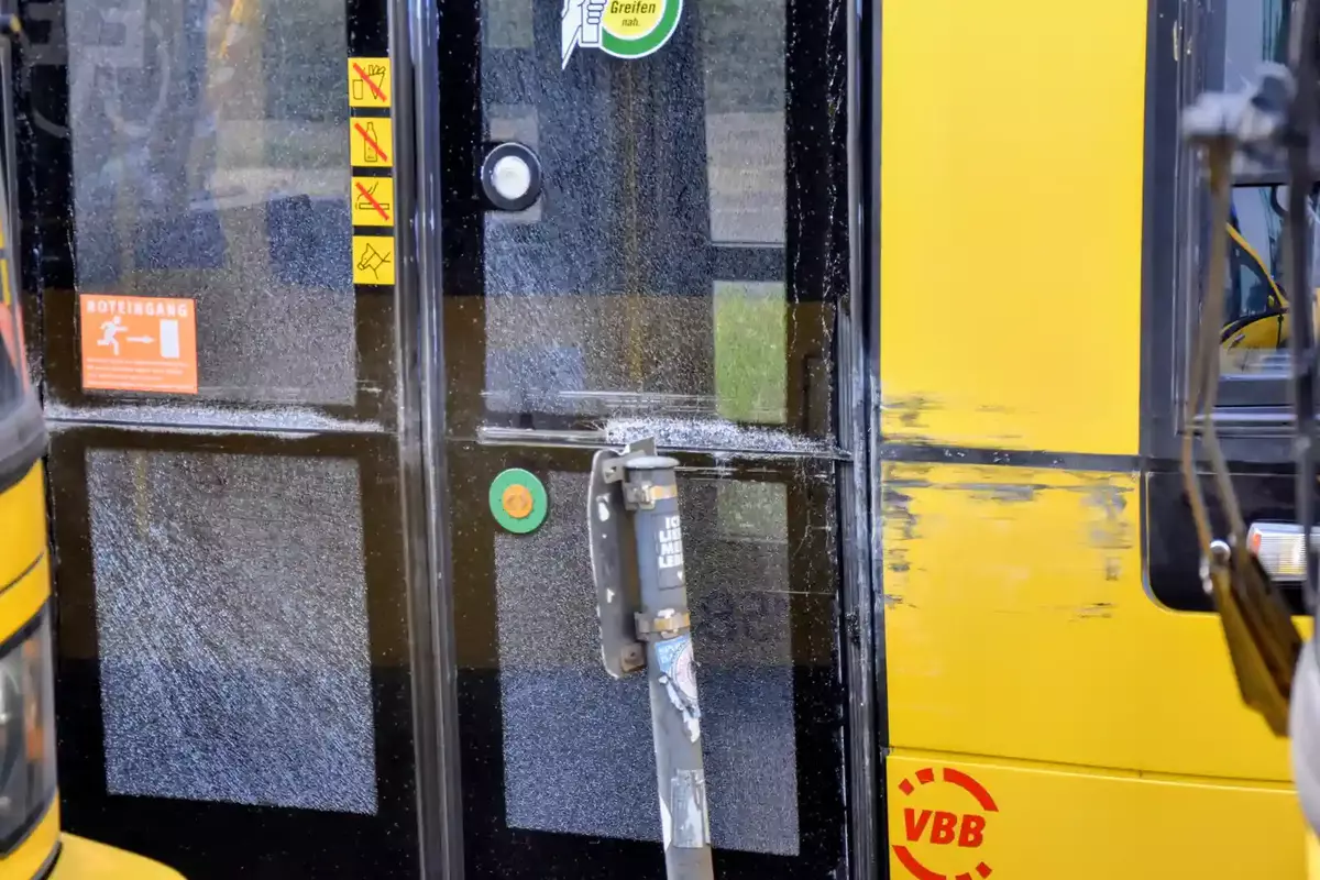 Gelbe Fahrzeugtür mit schwarzem Fenster, an der Tür sind die Scheiben gesplittert, rechts daneben schwarze Kratzer am Fahrzeuglack.