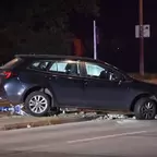 Dunkelblauer Kombi steht mit beschädigtem vorderem rechten Rad auf einer Verkehrsinsel, Feuerwehrmann in Schutzkleidung steht daneben.