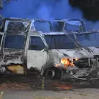 Zwei ausgebrannte Krankentransporter und rauchendem Hintergrund auf einem Parkplatz.