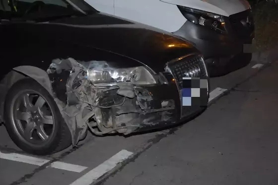 Schwarzes Auto mit stark beschädigtem vorderem rechten Kotflügel und Scheinwerfer, daneben weißer Transporter.