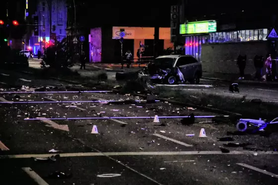 Zerstörter Pkw mit beschädigter Front auf einer nächtlichen Straße, umgeben von Trümmern und Markierungen auf der Fahrbahn.