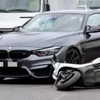 Dunkelgrauer BMW steht auf der Straße vor einem umgekippten weißen Motorroller.