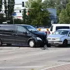 Schwarzer Transporter und weißer Kleinwagen mit beschädigten Fronten nach Zusammenstoß an Kreuzung, Trümmer auf Straße.