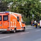 Zwei Einsatzfahrzeuge der Feuerwehr mit Blaulicht stehen an einer Straße, mehrere Einsatzkräfte in Uniform sind zu sehen.