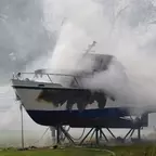 Boot auf Landgestell steht in dichtem Rauch, sichtbare Brandspuren am Rumpf.