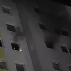 Mehrstöckiges Wohnhaus bei Nacht mit Rauch, der aus mehreren Fenstern dringt.