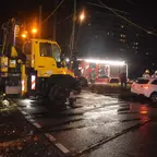 Unimog mit gelber Warnbeleuchtung zieht Mercedes aus dem Gleisbett bei Nacht, Feuerwehrfahrzeug und Einsatzkräfte im Hintergrund.