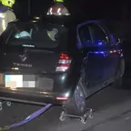 Schwarzer Renault Twingo auf Rollgleitern, zwei Feuerwehrleute stehen daneben bei Nacht