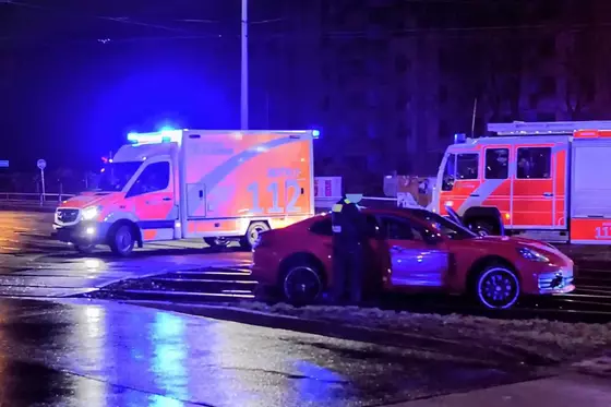 Roter Porsche steht im Gleisbett der Straßenbahn, im Hintergrund sind ein Rettungswagen und ein Feuerwehrfahrzeug mit Blaulicht zu sehen