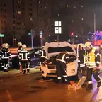 Feuerwehrleute in Schutzkleidung arbeiten nachts zwei beschädigte Autos an einer Kreuzung mit Einsatzfahrzeugen im Hintergrund.