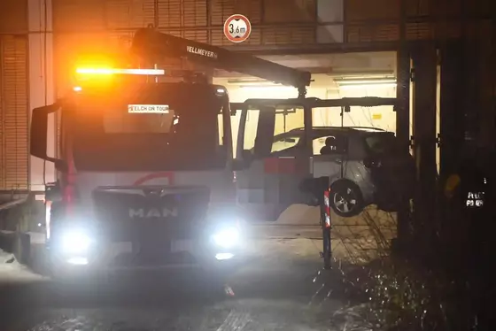 Abschleppwagen mit eingeschalteten Scheinwerfern und Warnleuchte hebt ein Auto in einer dunklen Garage