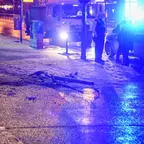 Umgelegter Ampelmast liegt auf nasser Straße, daneben stehen drei Polizisten und ein Polizeifahrzeug mit eingeschaltetem Blaulicht