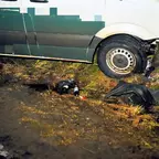 Zwei Weinflaschen, neben einem beschädigten Transporter an einem Baum.