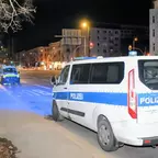 Polizeifahrzeuge mit Blaulicht stehen nachts an einer Straße vor einem Gebäude.